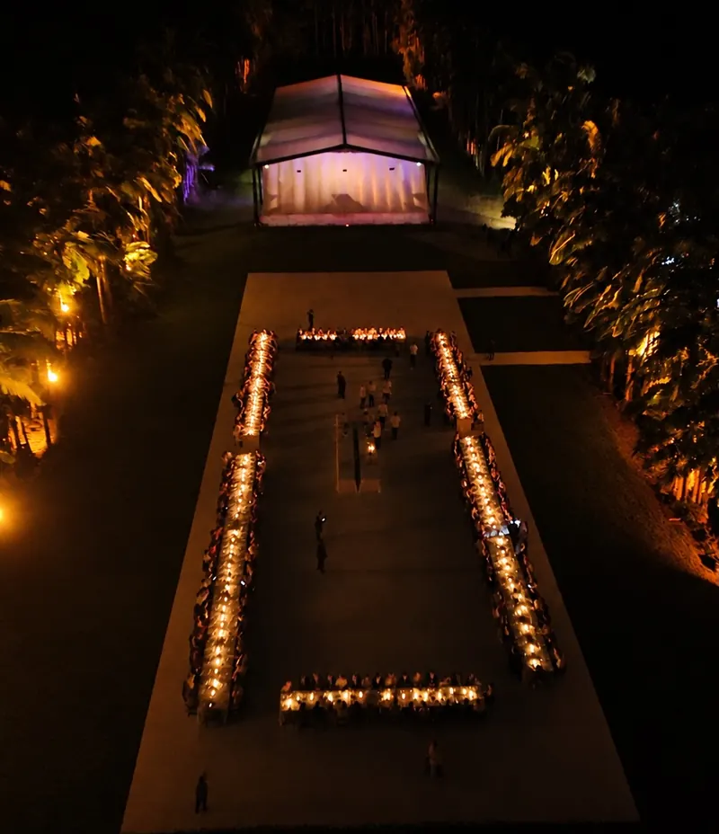 A mesa do jantar iluminada por velas no meio da alameda, vista do alto, à noite